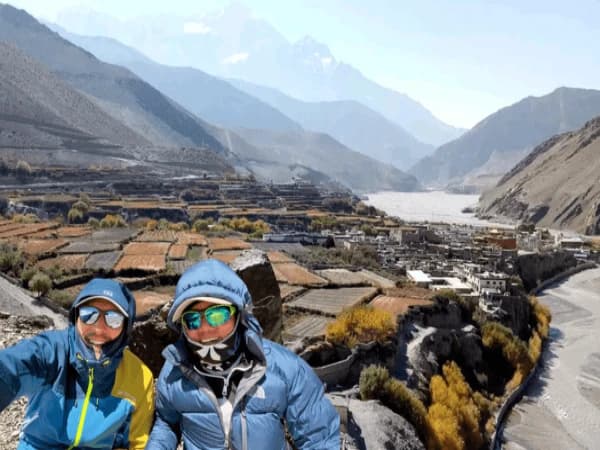Trekkers-overlooking-a-mountain-village-and-river-valley-in-the-Himalayas